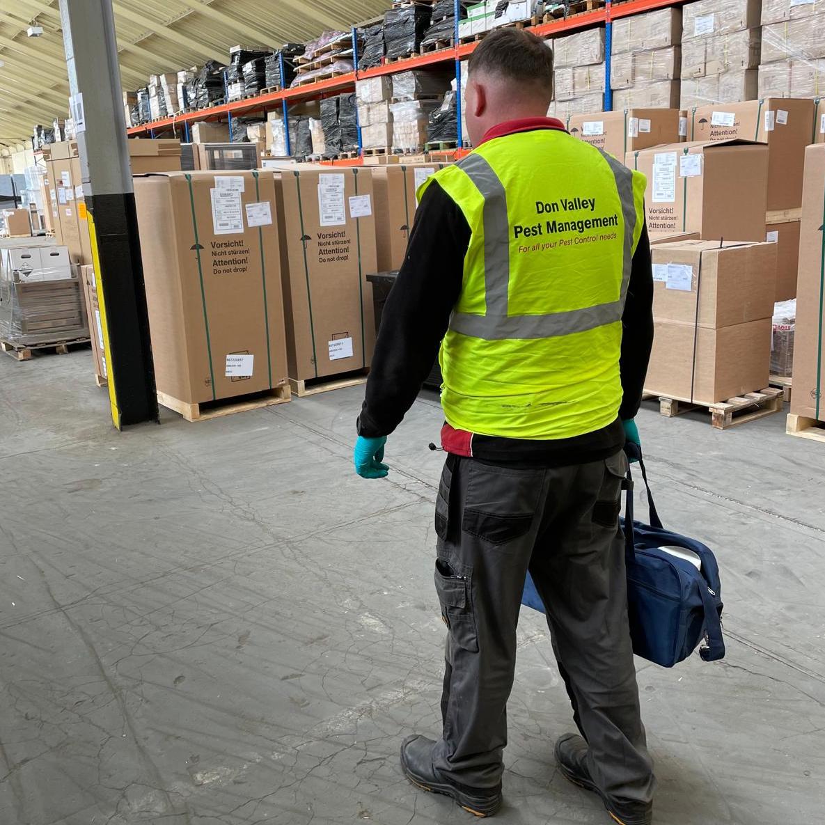 Don Valley pest controller in a branded high-vis vest attending a commercial pest control job at a warehouse.